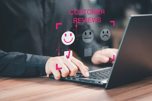 Customer service experience and business satisfaction survey. Man hand using a computer laptop with pop up smiley face icon for assessment feedback review satisfaction opinion and testimonial.