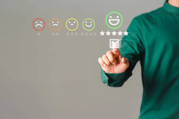 Customer\'s hand is touching virtual screen on the happy smile face icon to give satisfaction in service. Concept of assessment testimonial customer service and feedback, Opinion rating very impressed.