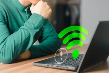 Yetişkin bir adam evindeki kablosuz internete bağlanmak için bilgisayar kullanıyor ama Wi-Fi çalışmıyor ve internet sitesinden dijital oyun verileri yüklemek için bekliyor..