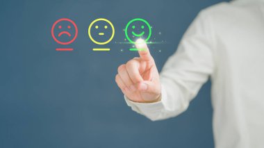 Müşterinin eli, hizmette tatmin olmak için gülen yüz ikonuna sanal ekrana dokunuyor. Değerlendirme kavramı beyan müşteri hizmetleri ve geri bildirim, görüş derecesi çok etkileyici.