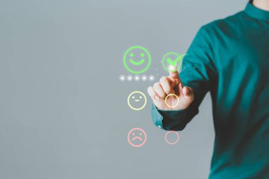 Müşterinin eli, hizmette tatmin olmak için gülen yüz ikonuna sanal ekrana dokunuyor. Değerlendirme kavramı beyan müşteri hizmetleri ve geri bildirim, görüş derecesi çok etkileyici.