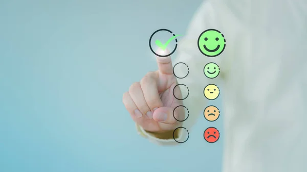 Customer hand touching the virtual screen on happy smile face icon to give satisfaction in service. Business concept of assessment testimonial customer service and feedback, Opinion rating very good.