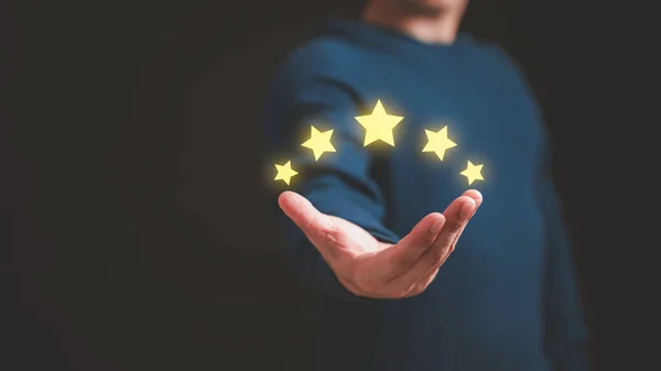 Customer hand showing the stars to complete five stars. Comment scores are good. Customer service assessment, testimonial, feedback, giving a five star rating. Service rating, satisfaction concept.