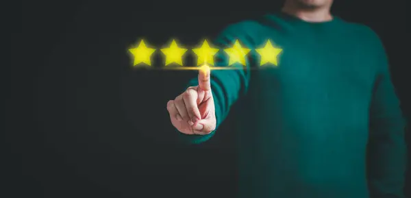 Customer hand touching the stars to complete five stars. Comment scores are good. Customer service assessment, testimonial, feedback, giving a five star rating. Service rating, satisfaction concept.