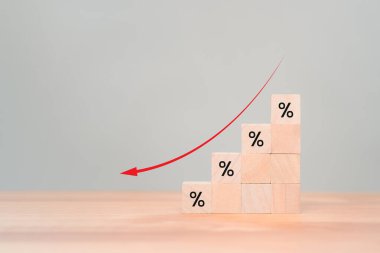 Yüzdelik işareti ve aşağı ok simgesiyle tahta küp blokları. Gelir azalması, yatırım azalması, ekonomik kriz, faiz oranı düşüşü, risk yönetimi.
