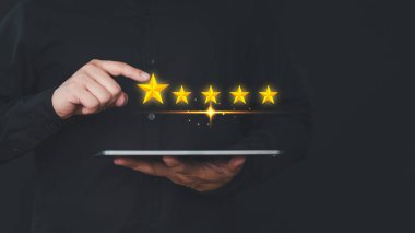 Tablet kullanan el, geri bildirim tatminini değerlendirmek ve ifade vermek için nokta beş yıldız simgesi verir. Müşteri hizmetleri deneyim değerlendirmesi ve iş memnuniyeti anketi.