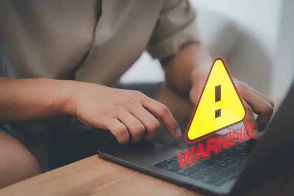 User man using a computer laptop with triangle caution warning sign for notification error. Concept technology of computer virus detected, personal data protection, network security and maintenance.