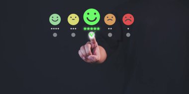 Müşteri eli, mutlu gülümseme yüz ikonu üzerinde sanal ekrana dokunur ve hizmette tatmin olur. Çevrimiçi değerlendirme konsepti beyan müşteri hizmetleri ve geri bildirim, görüş derecesi çok iyi.