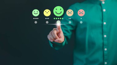 Müşteri eli, mutlu gülümseme yüz ikonu üzerinde sanal ekrana dokunur ve hizmette tatmin olur. Çevrimiçi değerlendirme konsepti beyan müşteri hizmetleri ve geri bildirim, görüş derecesi çok iyi.
