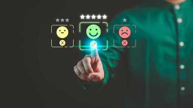 Müşteri eli, hizmette tatmin olmak için mutlu gülümseme simgesine sanal ekrana dokunuyor. Değerlendirme kavramı beyan müşteri hizmetleri ve geri bildirim, görüş derecesi çok etkileyici.