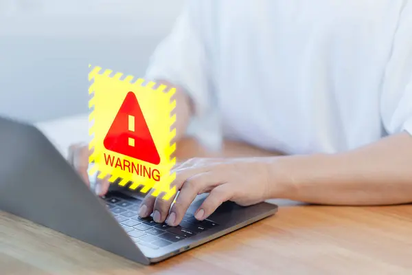 User using a computer laptop with caution warning sign for notification error. Concept technology of computer virus detected, personal data protection, network security and maintenance.