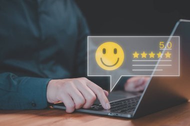 Müşteri, görüş ve hizmette tatmin olmak için gülen yüz simgesinde sanal ekran olan bir dizüstü bilgisayar kullanır. Müşteri memnuniyeti anketi, hizmet derecesi çevrimiçi, referans değerlendirmesi.