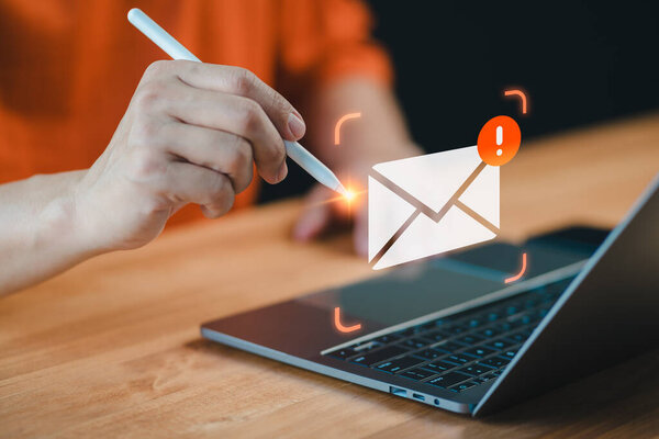 Man multitasks with a pen and laptop, A cautionary email alert notification symbolizes the importance of security measures against errors, ensuring internet protection amidst concerns like junk mail.