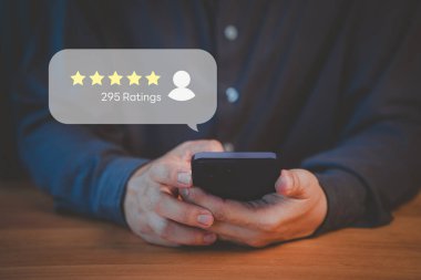 295 reyting gösteren beş yıldızlı bir akıllı telefon tutan kişi. Dijital arayüzde müşteri geribildirimi, çevrimiçi değerlendirmeler ve kullanıcı memnuniyetini temsil eden iş kavramı.