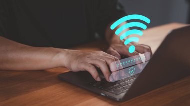 Kişi, Wi-Fi bağlantısı kullanarak bir dizüstü bilgisayara girip bir kullanıcı adı ve şifre giriyor. Teknoloji kavramı internet erişimini, çevrimiçi güvenliği ve kişisel veri korumasını vurguluyor.
