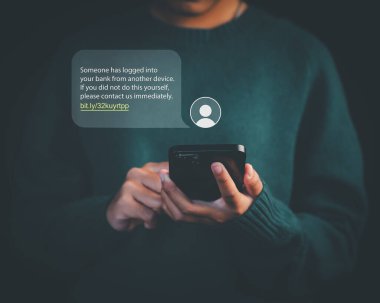 Banka girişi, internet dolandırıcılığı, siber güvenlik tehditleri, kimlik hırsızlığı ve internet güvenliği farkındalığını temsil eden sahte mesaj uyarısı içeren akıllı telefonu elinde tutan kişi.