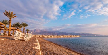 Morning on sandy beach of the Red Sea in Eilat - famous tourist resort and recreational city in Israel. Concept of bliss vacation and happy holiday  