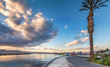 Ürdün dağları üzerindeki bulutlu hava ve güneş ışınları ve Akabe şehri, Kızıldeniz 'deki Akabe körfezi.