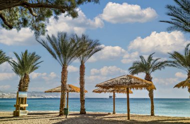 Morning on sandy beach of the Red Sea in Eilat - famous tourist resort and recreational city in Israel. Concept of bliss vacation and happy holiday  