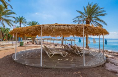Eilat 'taki Kızıldeniz' in merkez halk plajında güneşlik ve şemsiyeli bir dinlenme yeri - İsrail 'in ünlü turistik beldesi ve eğlence şehri. Mutlu tatil kavramı ve mutlu tatil.  