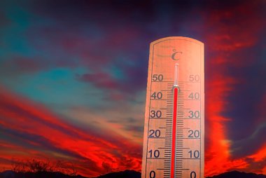 Küresel ısınma nedeniyle aşırı hava sıcaklığı ve kırmızı dramatik bulutlara sahip termometre. Gezegenimizdeki şiddetli iklim değişikliklerini sembolize eden kavramsal görüntü