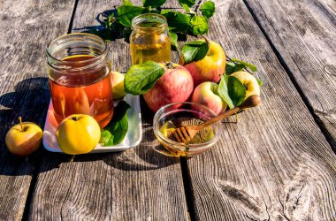 Kavanozlar dolusu tatlı bal ve elmayla kapatıyoruz. Yeni yıl Yahudi bayramının ana sembolleri. Rosh ha - Shanah. Şenlikli yemek özellikleri ahşap masa üzerinedir.