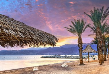 Eilat 'taki Kızıl Deniz' in kumlu sahilinde dramatik bir gün batımı - İsrail 'in ünlü turistik beldesi ve eğlence şehri