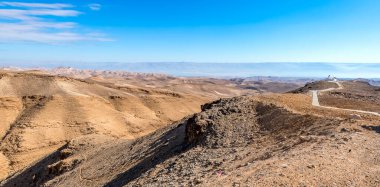 Arad şehri civarındaki Musevi Çölü 'ne bakın. Bulutlar ve mavi gökyüzü, sıradışı taş kanyon. Antik dağları çevreleyen ve ufukta ölü deniz.  