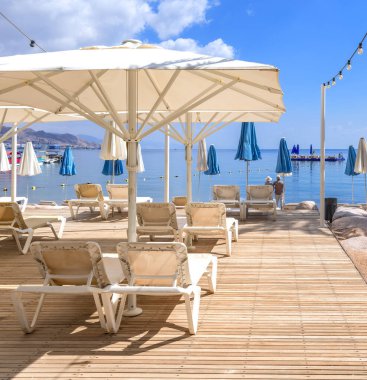 Kızıl Deniz 'in halk plajında sabah, ahşap döşeme, dinlenme ve turistler için dinlenme tesisleri 