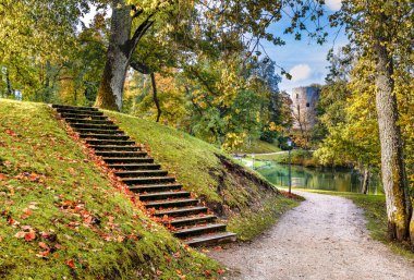 Sonbaharın altın mevsiminde, tepede ahşap merdivenler, gölet ve ortaçağ kulesi olan eski bir halk bahçesi parkı.
