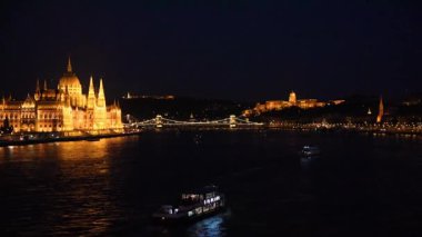 Günbatımında Macaristan 'ın Budapeşte kentinde Parlamento' nun inanılmaz manzarası, köprü ve gemiler. Büyüleyici yerler..