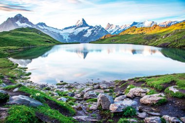 Gün doğumunda, İsviçre Alpleri 'ndeki gölün ön planında taşlarla muhteşem bir manzara. Wetterhorn, Schreckhorn, Finsteraarhorn ve Bachsee. Heyecan verici yerler. (rahatlama, uyum - kavram).