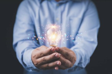 İş adamı ampulü elinde tutuyor ve arka planda fotokopi alanı var. Yaratıcılık yeniliği yeni teknoloji ve gelecekte iş için yeni fikirler. İlham, yenilik kavramları.