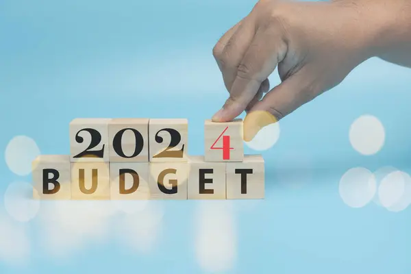 New year business planning budget and allocation 2024. Hand of man putting 2024 with Budget on wooden cubes blocks with copy space. Budget planning next years, investment, new business concept.