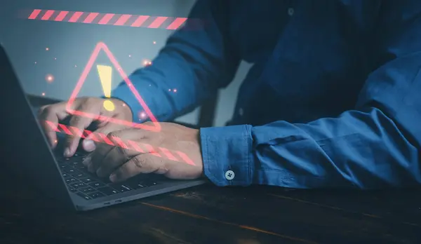 ビジネスマンがオフィスでラップトップコンピュータに取り組んでおり 警告警告通知マークが表示されます コンピュータネットワークへのサイバー攻撃 サイバーセキュリティとサイバー犯罪 ストック写真