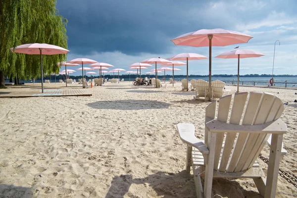 stock image Cloudy sky on the beach with the pink beach umbrellas and Adirondack chairs