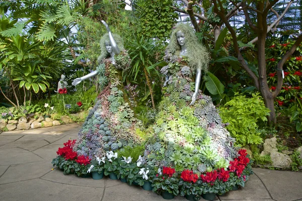 Konservatuarda bitki ve çiçeklerle kaplı mankenlerin görüntüsü