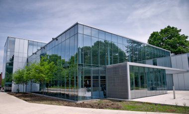 Modern bir kampüs binası. Çağdaş mimariyi simgeleyen parlak cam bir cephesi var..