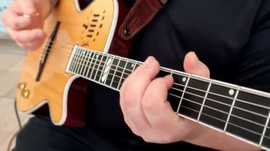 Gitaristin ellerinin yakın çekimi evde akustik gitarla akorlar çalıyor..