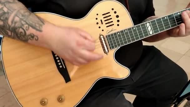 若い男がアコースティックギターの弦と音楽の音を演奏する — ストック動画