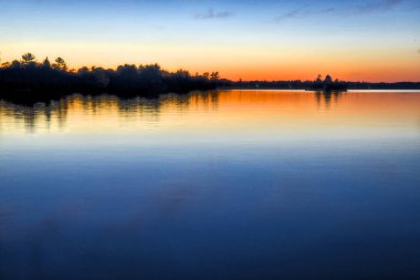 Alacakaranlıktaki gölün renkli su yansıması. Gravenhurst, Ontario, Kanada.