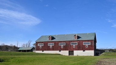 Kırmızı ahır ve mavi gökyüzü olan tarım arazisi