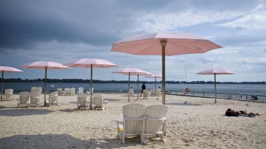 Kamu parkında pembe plaj şemsiyeleri ve Adirondack sandalyeleri.