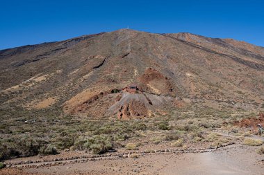 Tenerife, İspanya 'da güneşli bir yaz gününde kayalar ve kumla kaplı dikey bir volkan manzarası.