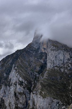 Kordillera Cantbrica, picos da europa, Leon, asturias, İspanya 'da yaz boyunca bulutlarla birlikte güneşli bir günde yürüyüş patikası olan büyük, güzel, gri bir dağ sırası.