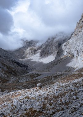 Kordillera Cantbrica, picos da europa, Leon, asturias, İspanya 'da yaz boyunca bulutlarla birlikte güneşli bir günde yürüyüş patikası olan büyük, güzel, gri bir dağ sırası.