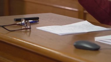 Profesör üniversitede ders veriyor. Profesörün elleri, öğretmenlik yaparken masanın üzerinde.