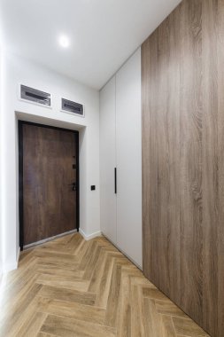 Ayna ve ışıklandırması olan yeni bir binada parlak ve ferah bir koridor.