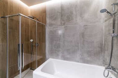 Temiz, gri fayanslı yeni bir banyo.