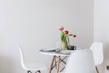 Yeni bir dairede beyaz arka planda sandalyeli bir masa.